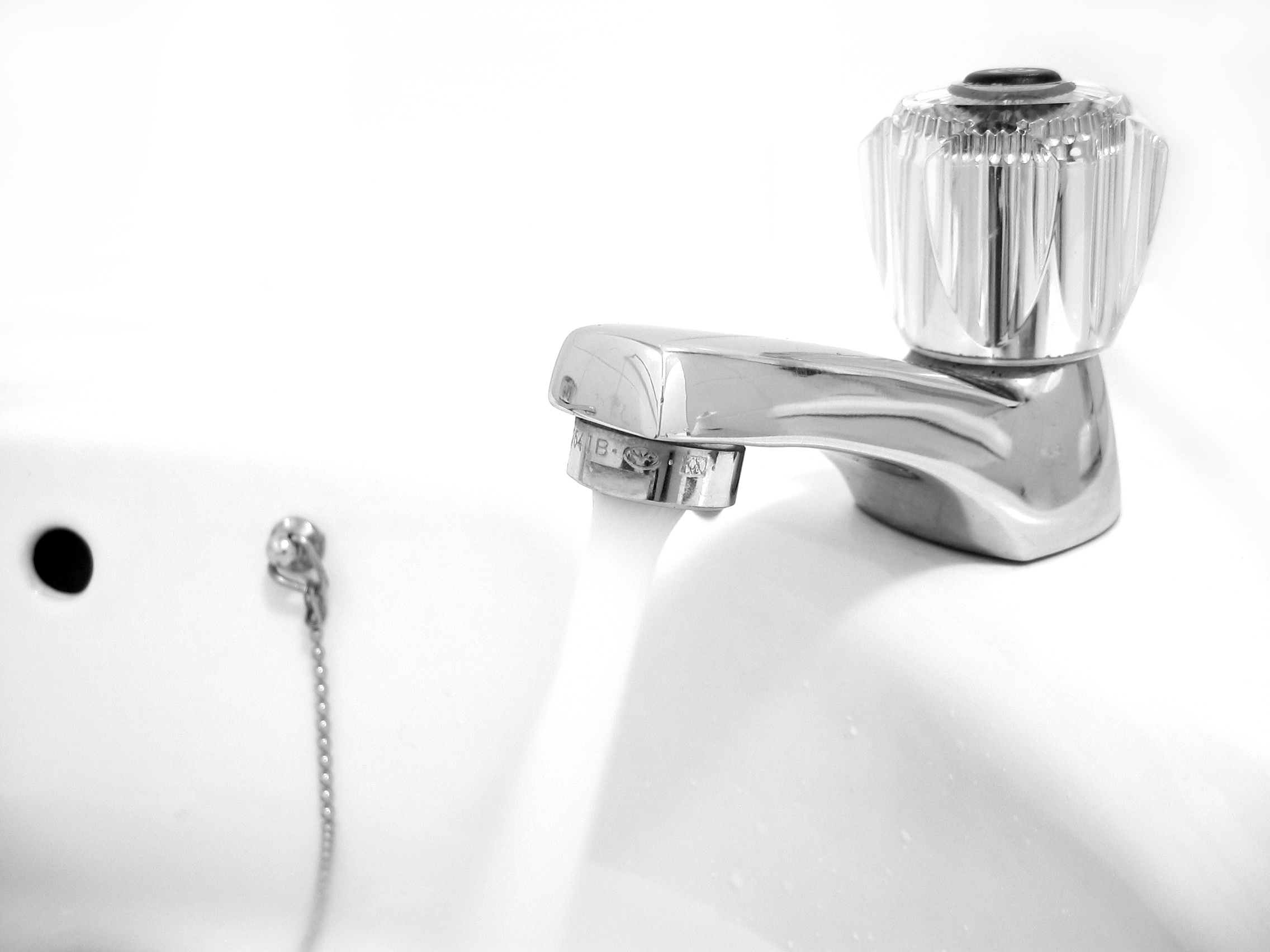 Close-up of a chrome household faucet with water running into a white sink. Water runs from a household faucet. Illustrative photograph; this is not an Old River or South Kern water-system location.