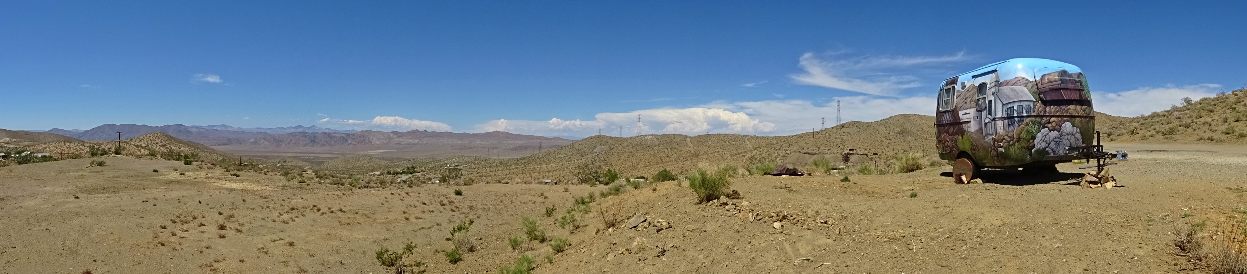 A wide desert landscape in the Randsburg area, with a painted travel trailer on the right.