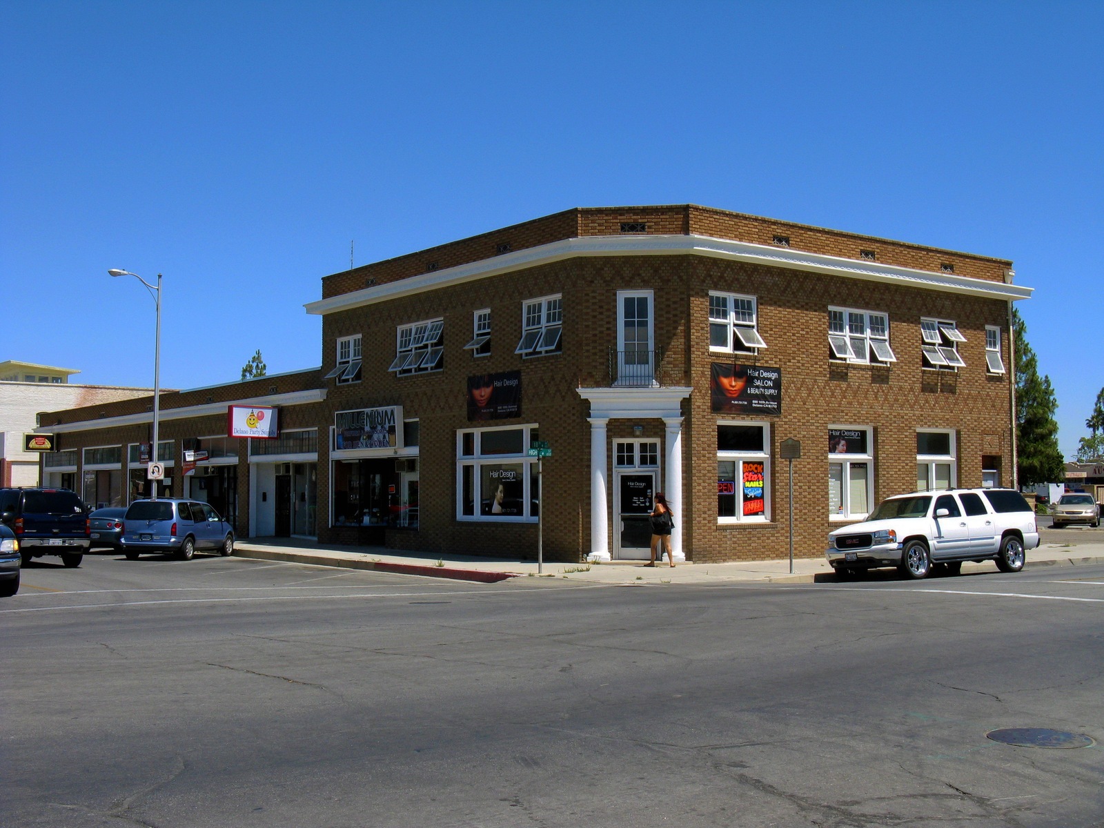 The two-story DeVenney and Turner commercial building at a street corner in Delano, with parked vehicles and a blue sky.