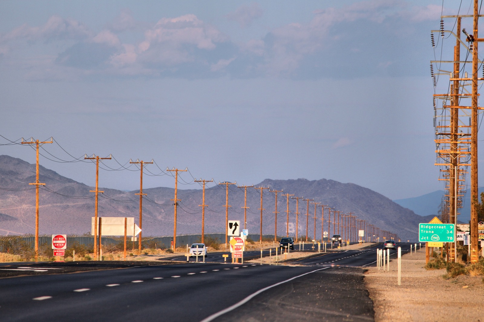Route 178 in Inyokern with wooden utility poles beside the roadway and mountains in the distance.