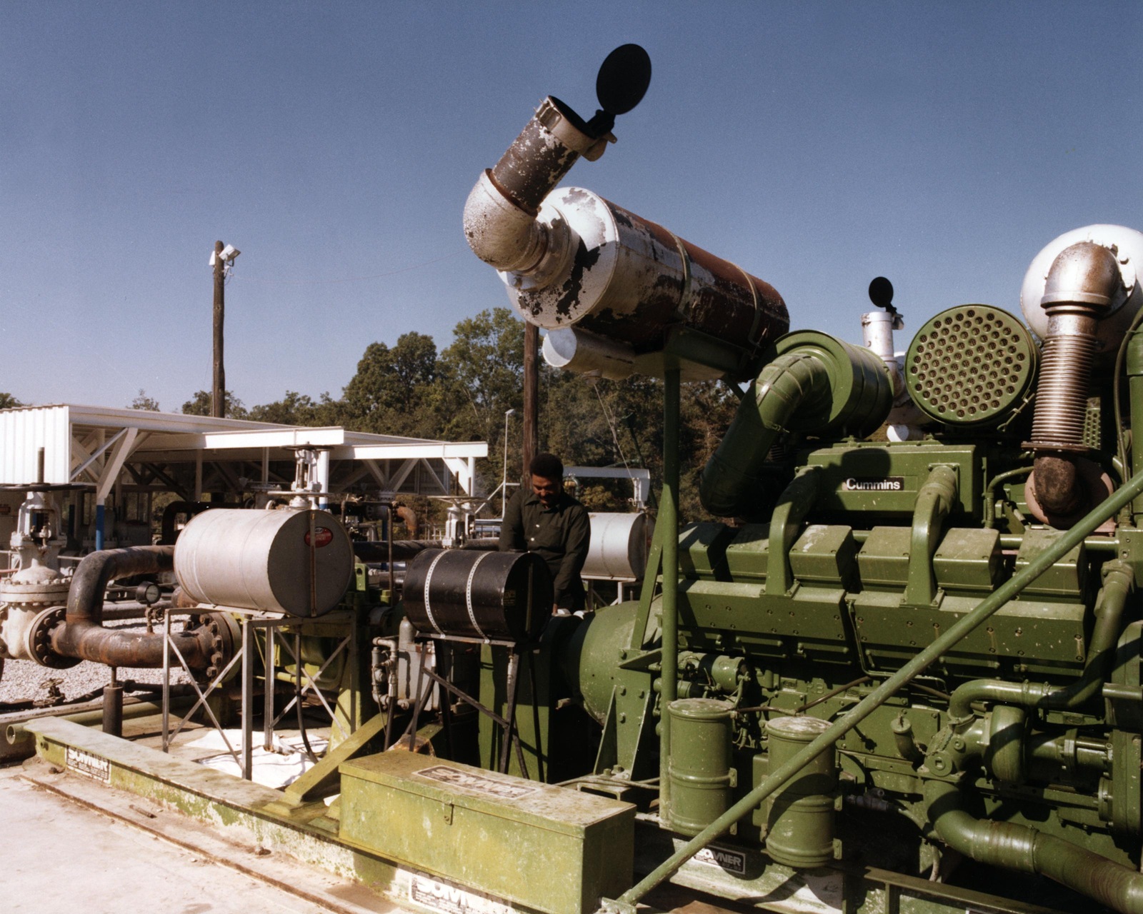 An archival photograph of large green pump equipment and piping at Bull Bay, with a worker between the machinery.