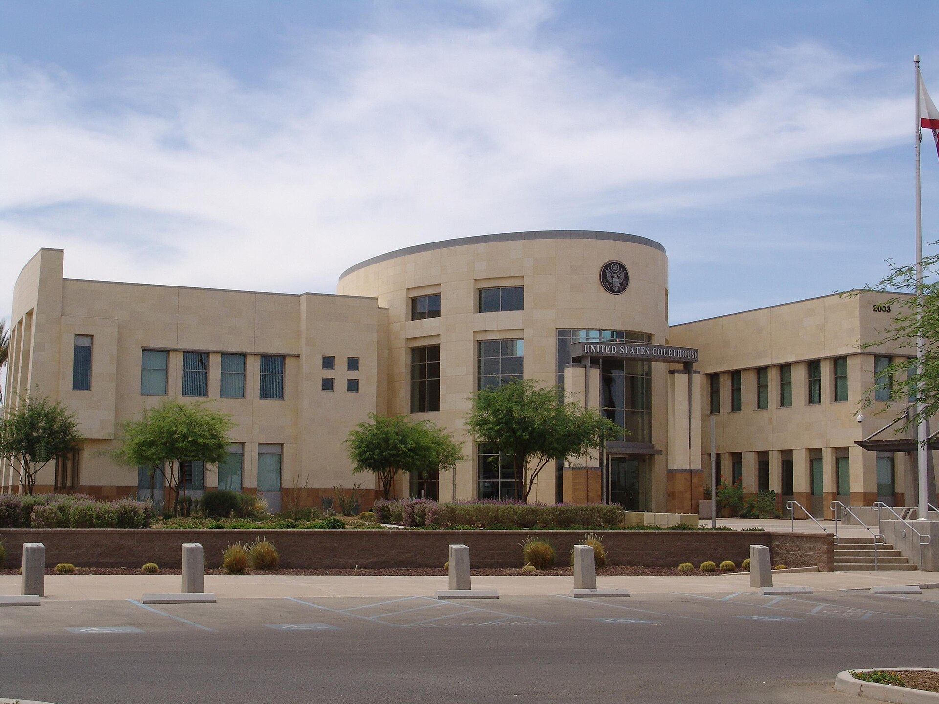 The United States courthouse in El Centro, California, with palm trees and parked cars outside.