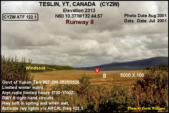 A paved airport runway stretches toward low mountains under a cloudy sky.