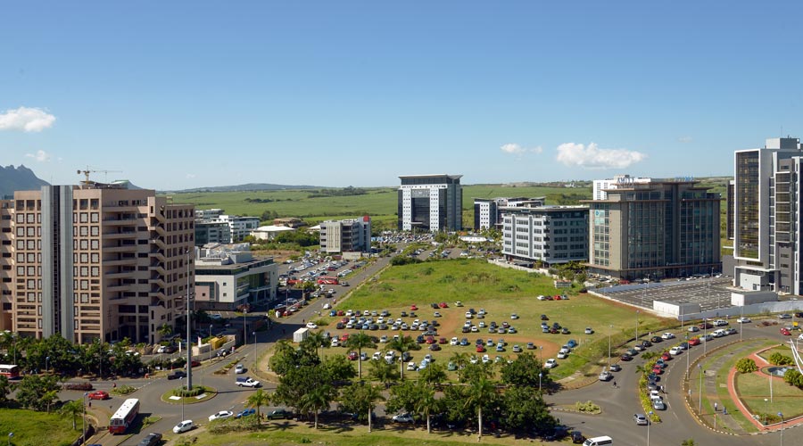 Office buildings rise behind landscaped grounds in a business park.