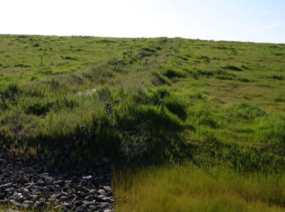A drainage channel runs down the slope of the former Fresno municipal landfill.
