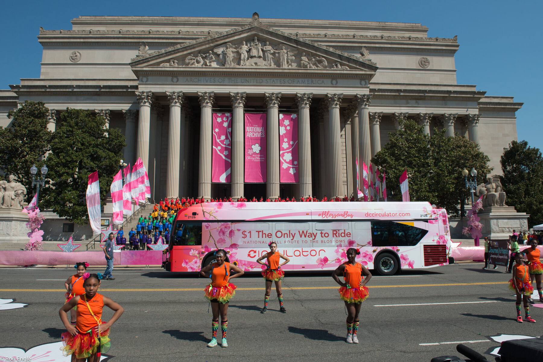 A public transit bus with a cherry-blossom wrap passes the National Archives in Washington, D.C.